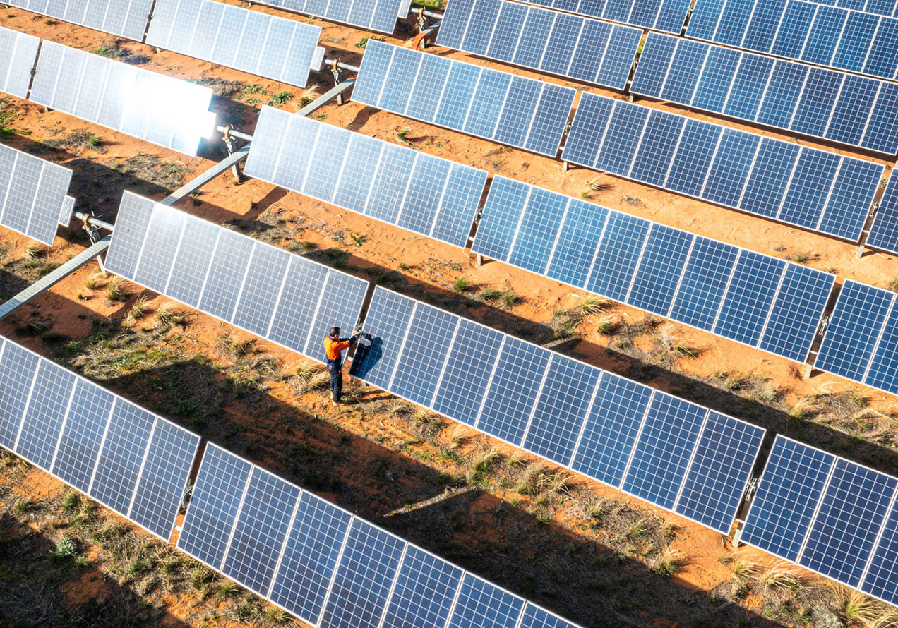Workers in high-visibility vests on a solar panel farm
